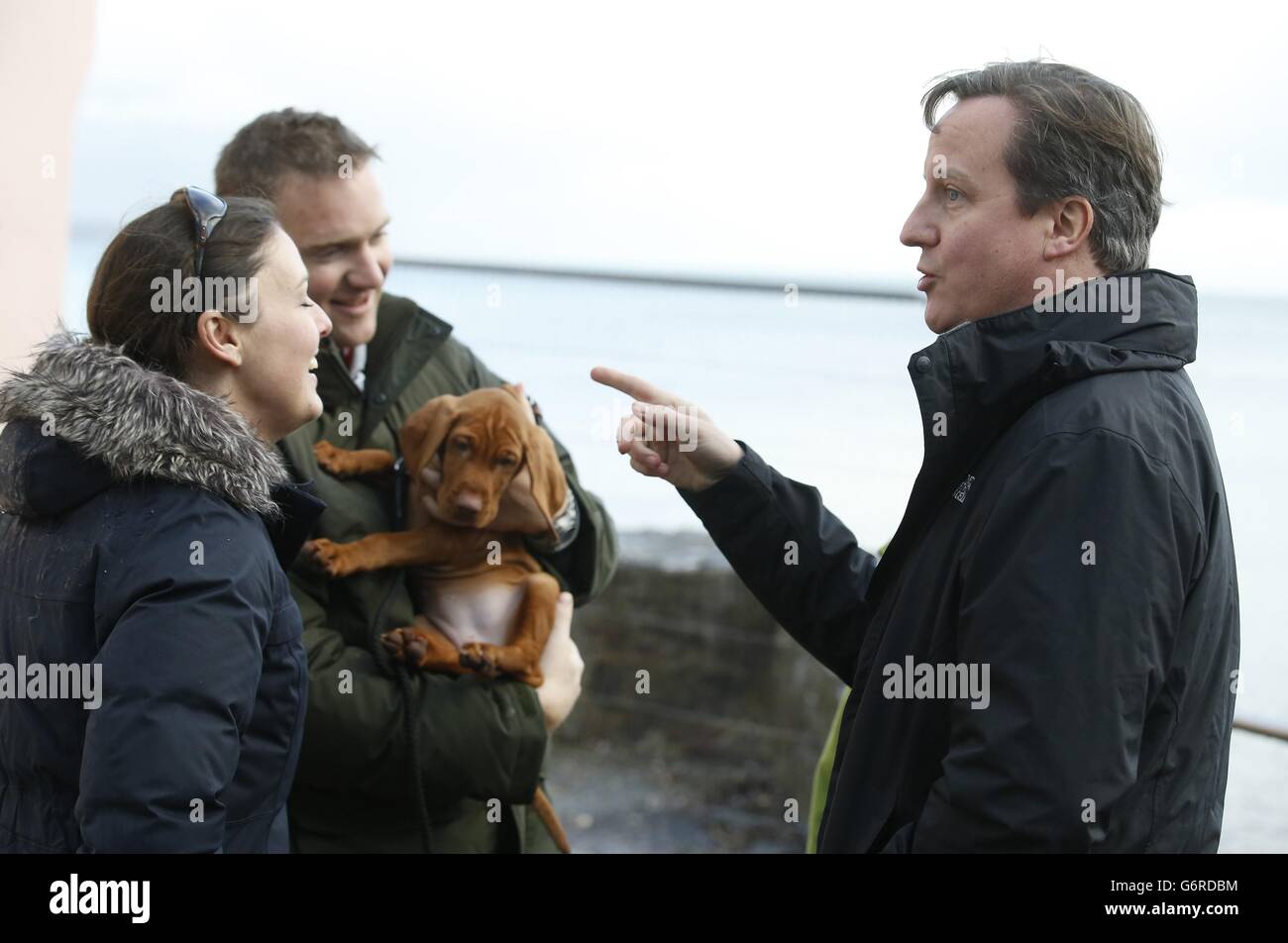 Prime Minister David Cameron (right) speaks to Nicky Hughes and John Brown, whose home was damaged during recent storms in Kingsand in Cornwall. Stock Photo