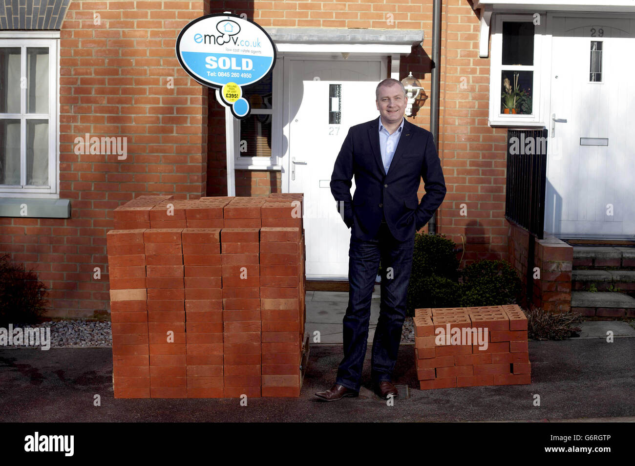 Russell Quirk, Founder of low cost online estate agency eMoov.co.uk, compares the different levels of commission earned comparatively by UK high street estate agents versus eMoov.co.uk, represented by piles of bricks outside a property in Brentwood, Essex. Stock Photo
