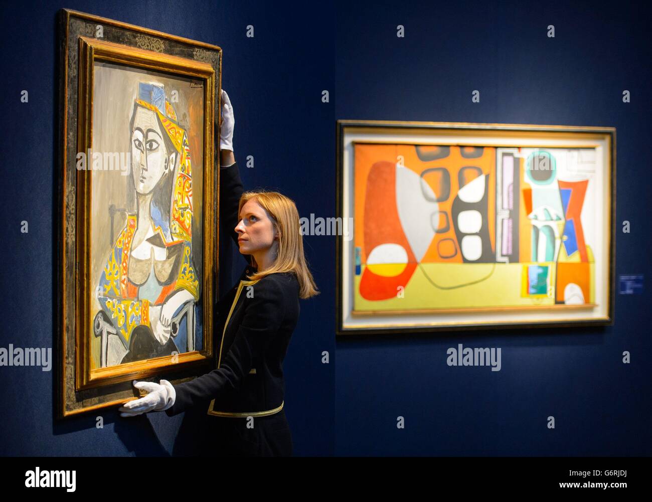 Christie's employee Amber Hailes adjusts Pablo Picasso's 'Femme au costume turc dans un fauteuil', 1955, which is expected to fetch &Acirc;&pound;15 million, next to the &Acirc;&pound;300,000 estimated painting 'Annibal Simla' by Le Corbusier, as part of Christie's Impressionist, Modern and Surrealist Art sale next month. Stock Photo