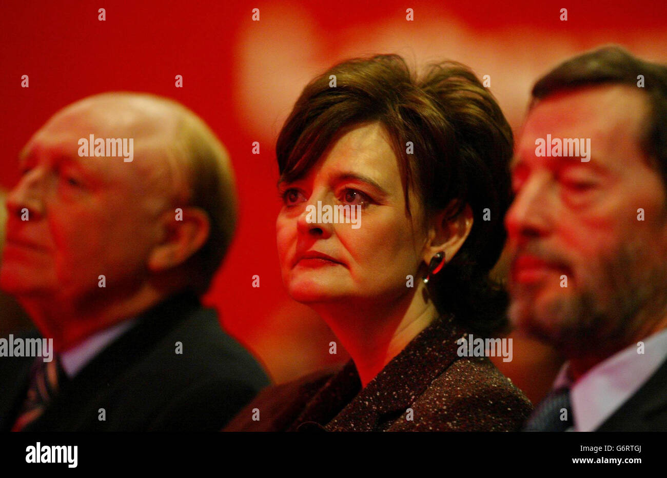 Cherie Blair, listens to her husband's keynote speech as she sits between former Labour leader Neil Kinnock (left) and Home Secretary David Blunkett, on the second day of the Labour spring conference at the Manchester International Conference centre. Mr Blair acknowledged that today's conference, designed originally as a tub-thumping exercise ahead of local council and MEP elections in June, 'takes place under the shadow of events in Spain'. Stock Photo