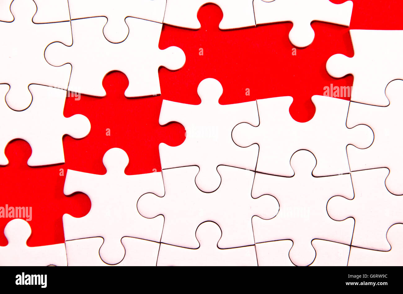 white jigsaw/puzzle wite some gaps over red background, symbol of problem solving Stock Photo