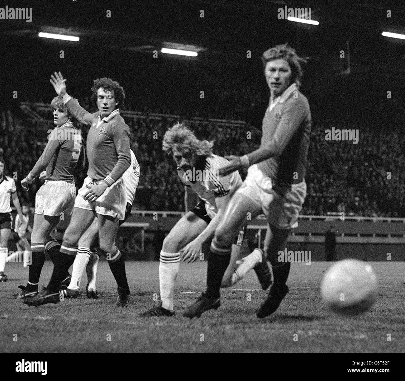 Fulham's Kevin Lock (second right) causes problems for the Manchester United defence in the FA Cup forth round tie at Craven Cottage. United's players are (l-r): Gordon McQueen, Stewart Houston and Brian Greenhoff. Stock Photo