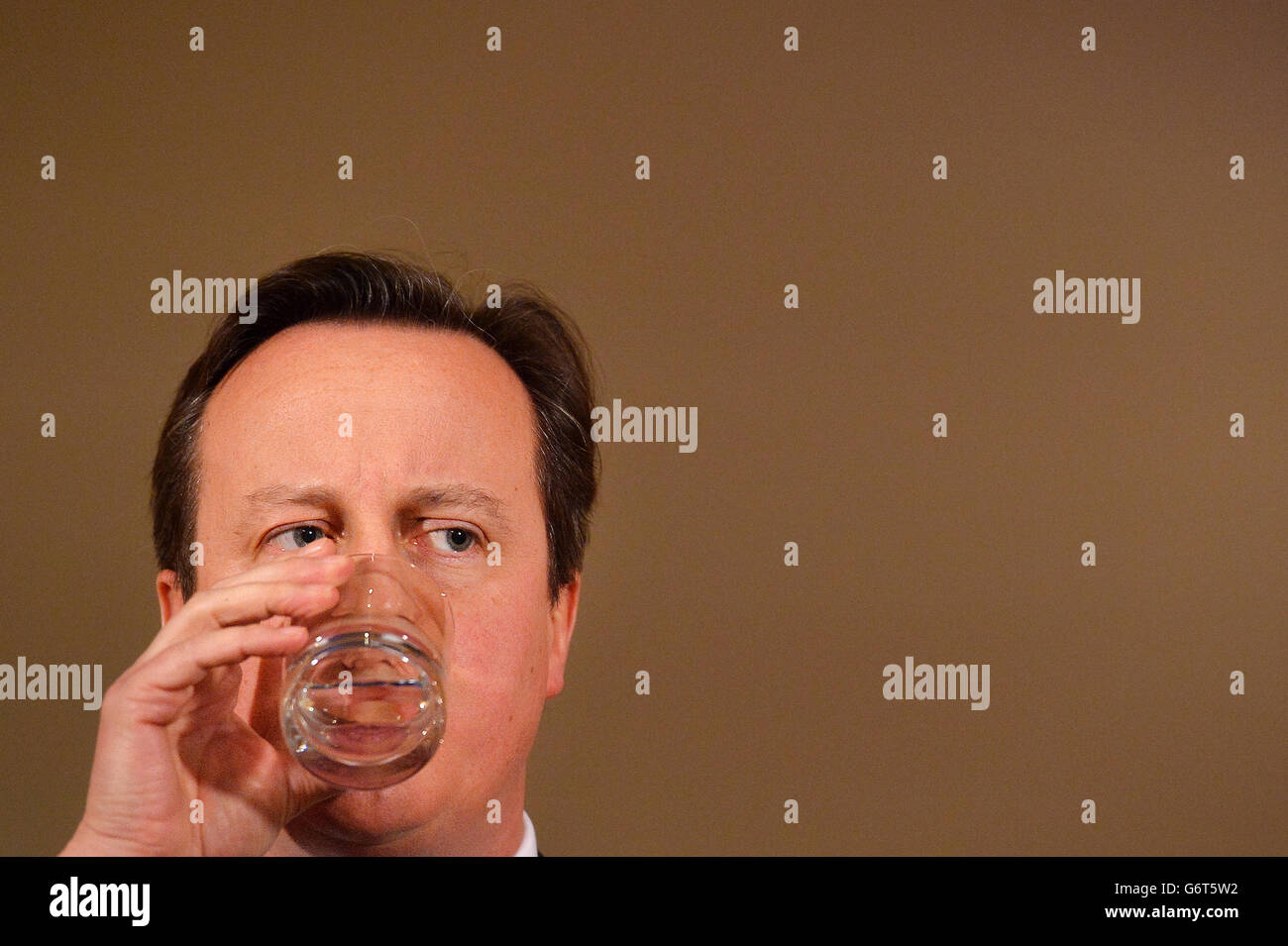 Prime Minister David Cameron pauses to take a drink as he addresses the media during a press conference in 10 Downing Street, London, where he promised that 'money is no object' in providing relief to communities affected by floods, as he warned that the country faces 'a long haul' to recover from the devastation of recent weeks. PRESS ASSOCIATION Photo. Picture date: Tuesday February 11, 2014. Fresh from a two-day tour of inundated communities in South-West England and the Thames Valley, the Prime Minister announced he was cancelling a planned trip to the Middle East to take personal charge Stock Photo