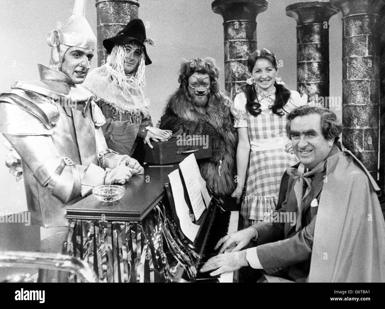 Joining in the Christmas fun is Chancellor of the Exchequer Denis Healey during rehearsals for Nationwide's version of 'The Wizard of Oz', to be broadcast on BBC One. In this scene, set at the turnstile of the wizard's castle, Nationwide presenters Sue Lawley (as Dorothy), John Stapleton (Tin man), Bob Wellings (Straw man) and Richard Stilgoe (Lion) encounter Mr Healey, who is cloaked and playing 'Over the Rainbow', with a red despatch box perched on the piano. Before anybody can pass Healey asks for a contribution to the IMF - the International Magicians' Fund. Stock Photo