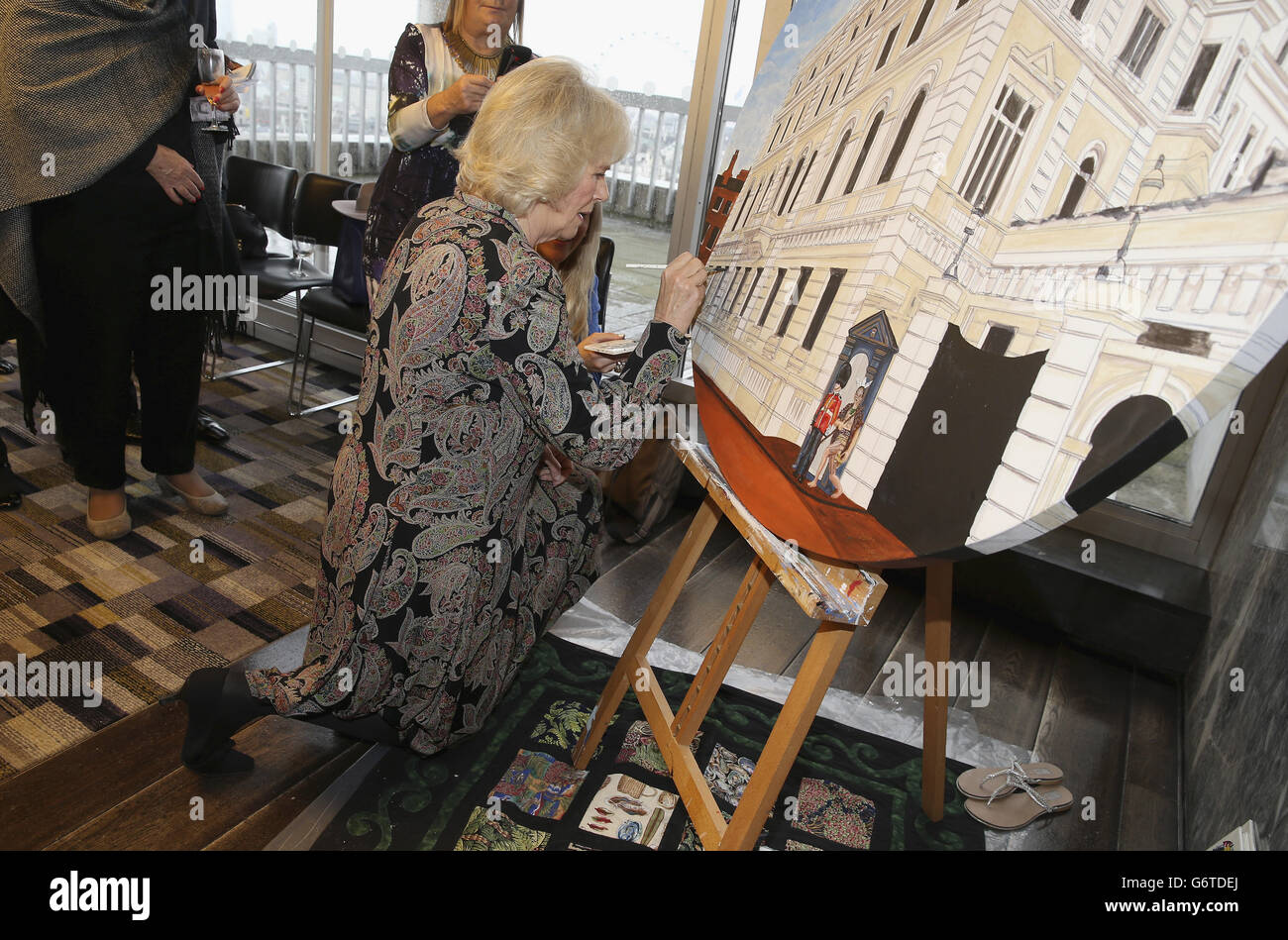 The Duchess of Cornwall helps put the finishing touches to NZL artist Mandii Pope's Maori-themed painting of Clarence House during a celebration of the success of New Zealand women in the UK on Waitangi day held at New Zealand House, central London. Stock Photo