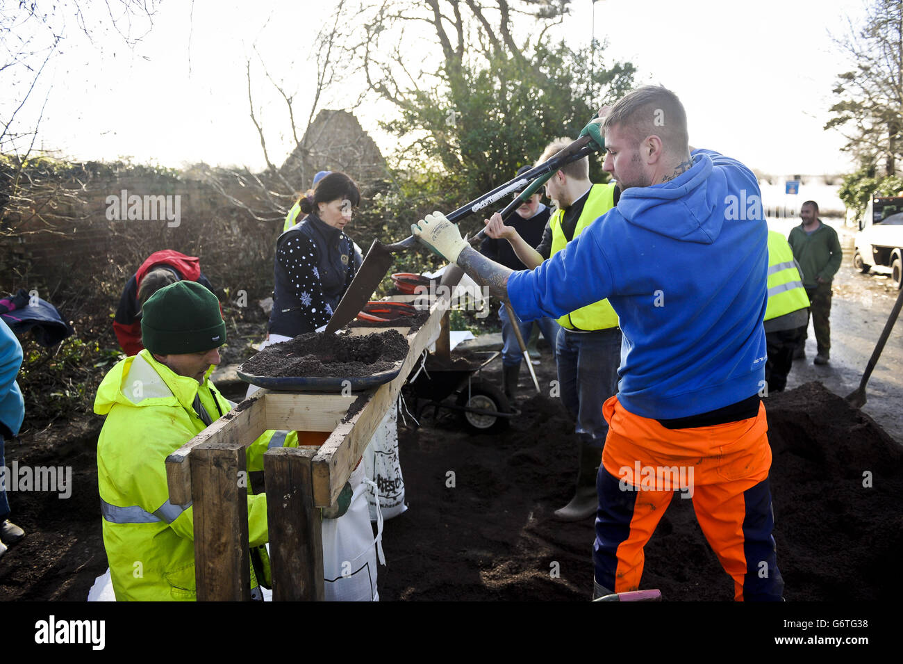 Volunteers help to fill and stack sandbags to help bolster flood defences at Burrowbridge in Somerset. Stock Photo