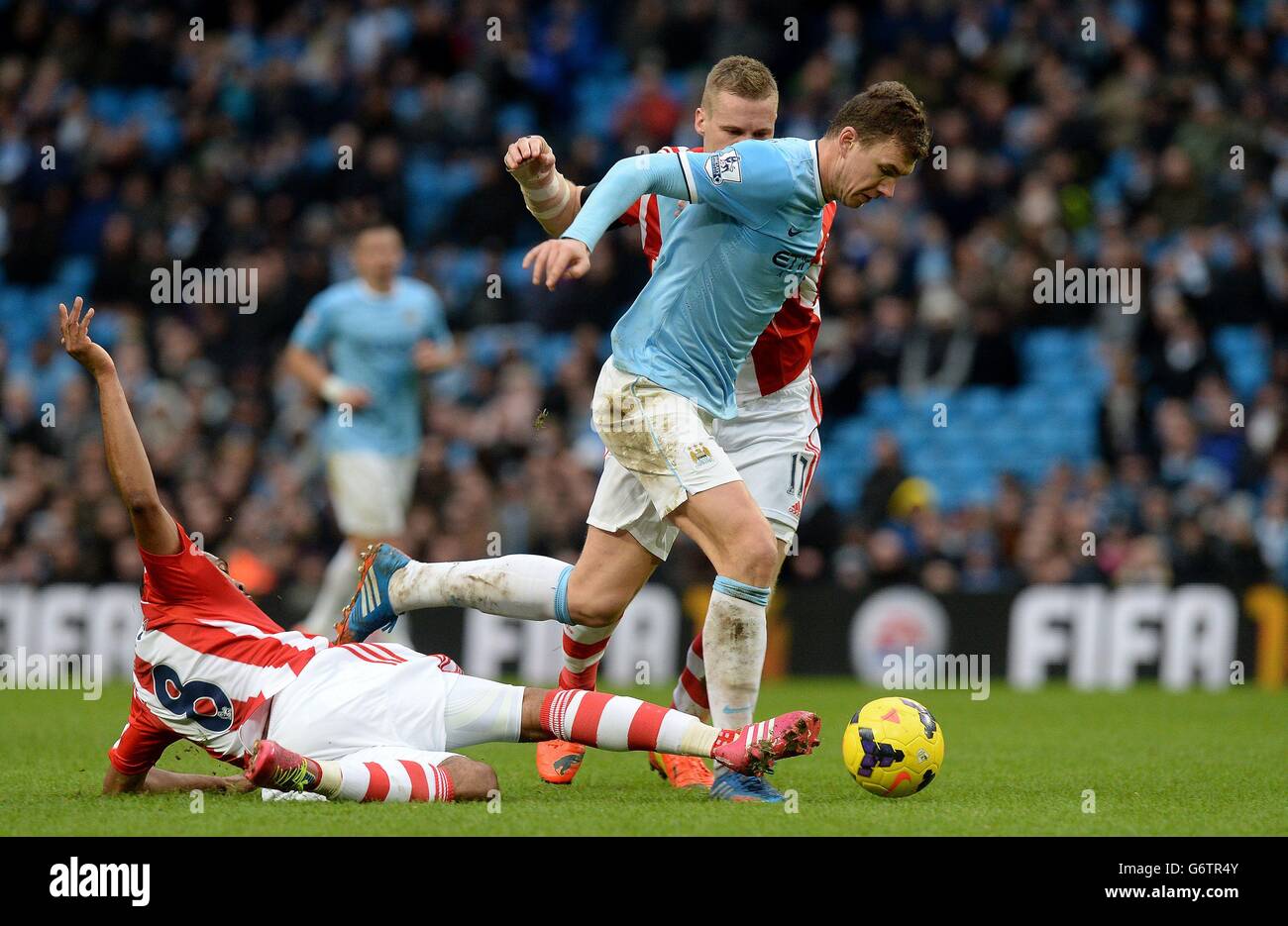Manchester City's Edin Dzeko battles for the ball with Stoke City's Ryan Shawcross (right) and Wilson Palacios (left), during the Barclays Premier League match at the Etihad Stadium, Manchester. Stock Photo