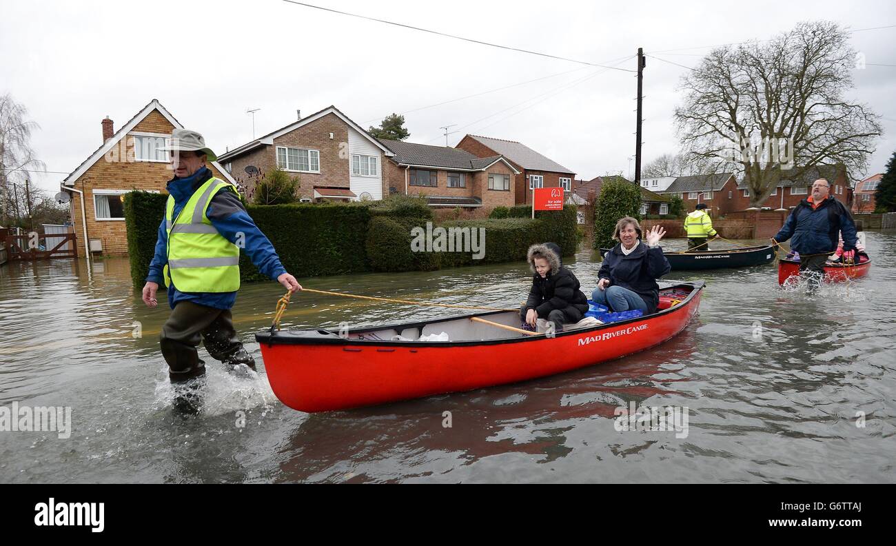 A local volunteer helps ferry local residents of Purley on Thames up a flooded street. Stock Photo