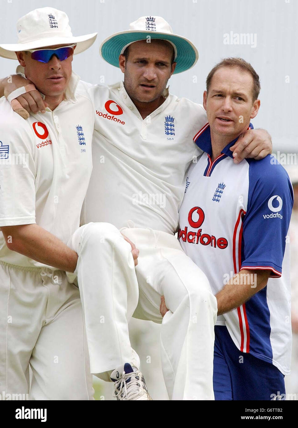 JAMAICA OUT : England's Mark Butcher is carried off the field by Ashley Giles (left) and team physiotherapist Kirk Russell after injuring his ankle, during the second day of the first tour match against Jamaica, at Sabina Park, Kingston, Jamaica. Stock Photo