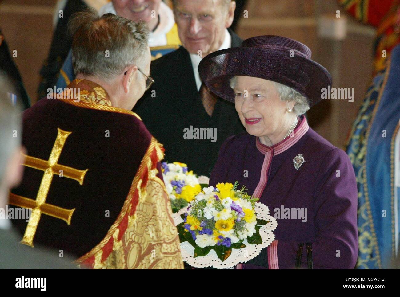 Queen Elizabeth II with the Duke of Edinburgh, is greeted by the Reverend Rupert Hoare, during the Royal Maundy Service held at Liverpool's Anglican Cathedral. The Queen arrived in Liverpool wearing a purple suit with a pink trim and matching hat, to take part in the ancient Maundy Thursday ceremony. Stock Photo