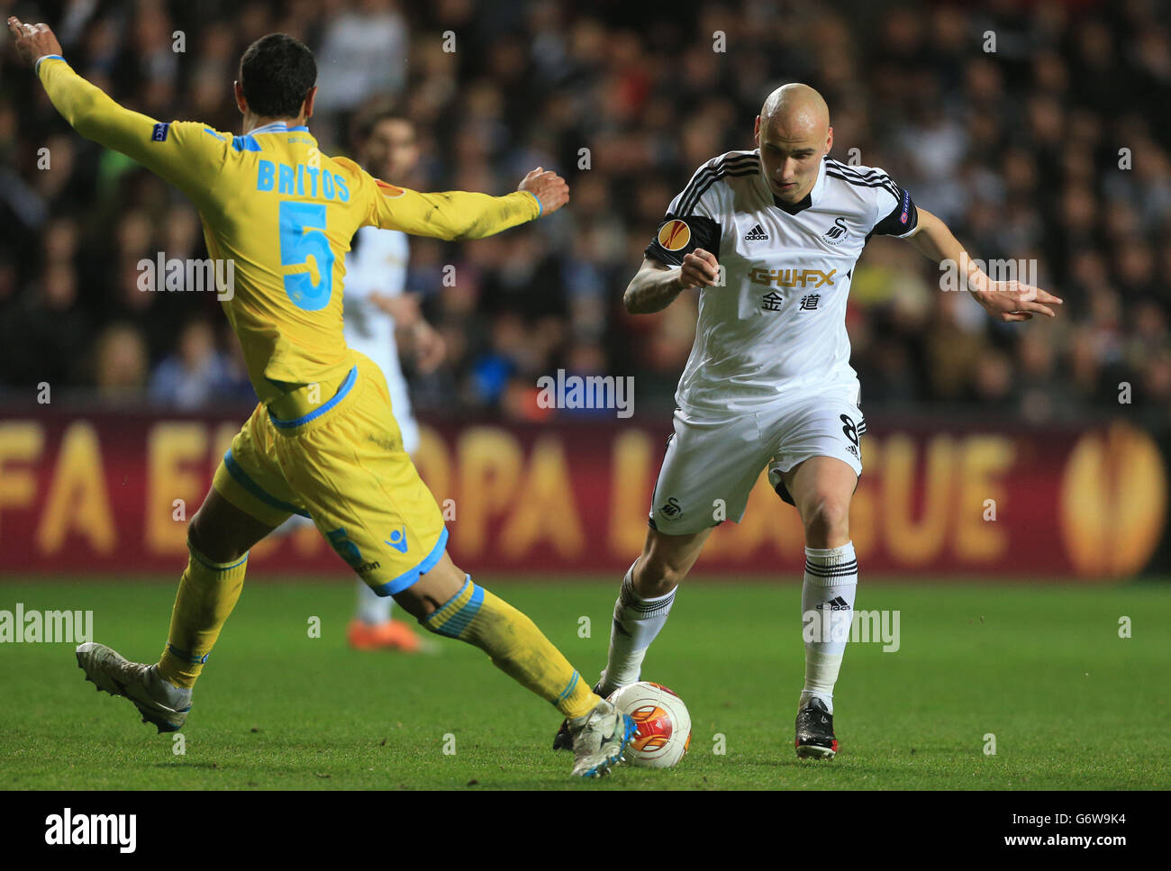 Swansea City's Jonjo Shelvey skips over tackle by Napoli's Miguel Britos during the UEFA Europa League, Round of 32 match at the Liberty Stadium, Swansea. Stock Photo