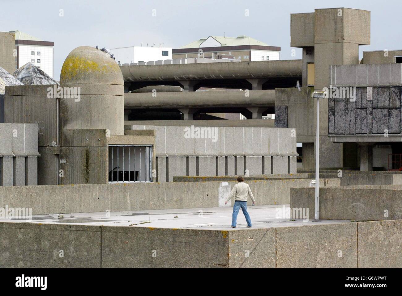 A lone figure walks through Britain's ugliest building, the Tricorn Centre, in Portsmouth. The 1960's shopping centre and car park which regularly topped the charts of unpopular sites in the country will start to be demolished after a brief and unsuccessful campaign to save it. 50,000 tonnes of grey ageing concrete will eventually disappear after nine months when a new complex will emerge. Stock Photo