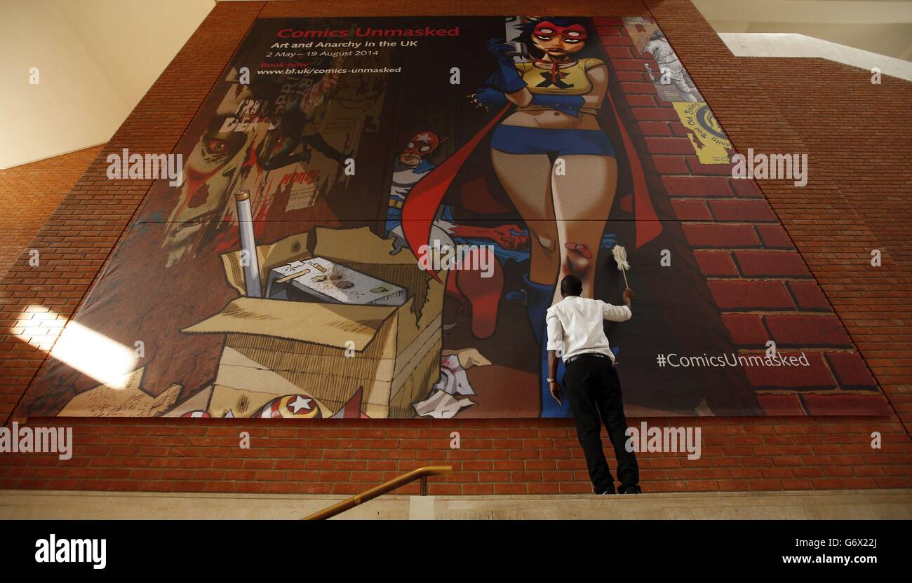 A British Library member of staff dusting the installation of a tapestry style poster of artwork by Gorillaz co-creator Jamie Hewlett, that was commissioned for the upcoming exhibition 'The Comics Unmasked: Art and Anarchy in the UK' at The British Library, central London. Stock Photo