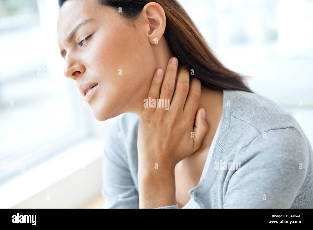 MODEL RELEASED. Young woman touching her neck in pain Stock Photo - Alamy