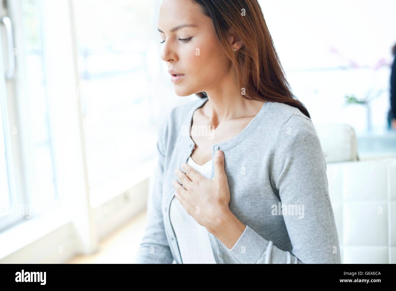 MODEL RELEASED. Young woman with her hand on her chest. Stock Photo