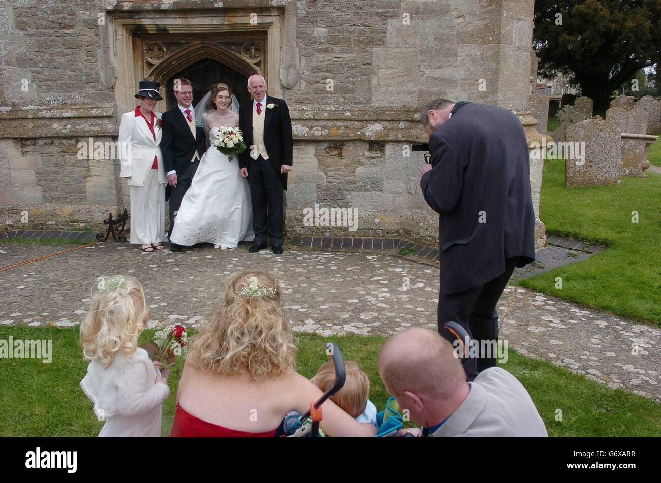A photographer takes a wedding photograph of happy couple Matthew and Rebekah Jones after they had been married at St Mary Magdalene Chuch in South Marston, near Swindon in Wiltshire, Saturday April 3, 2004. Matthew has now become the 11th generation in his family to marry in the same church as part of a tradition stretching back to 1690. Matthew, 28, had to seek special permission to continue this tradition, now that he lives in Rugby, in order to marry his bride, Rebekah, who hails from Devon. PA Photo : Johnny Green. Stock Photo