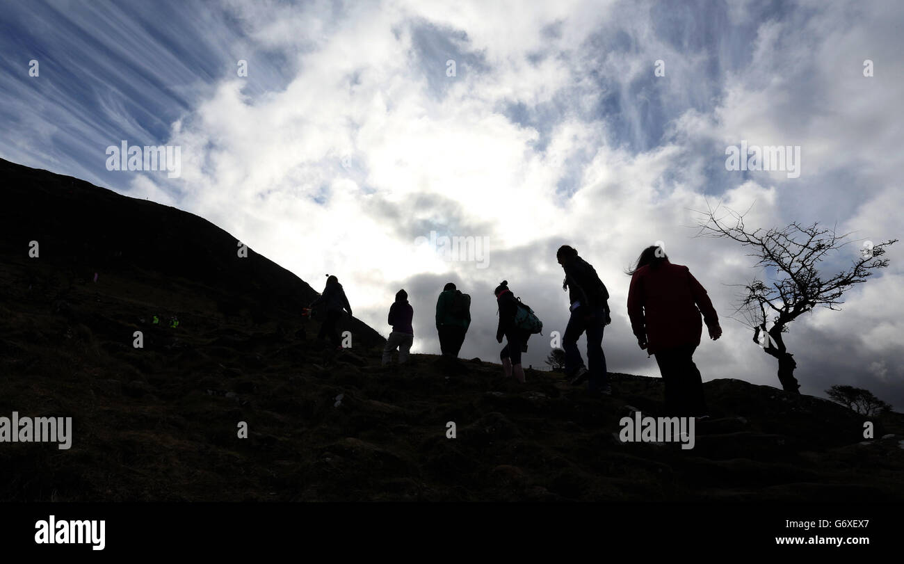 People silhouetted against the skyline, as the annual St Patrick's Day climb of Slemish mountain gets underway in Co Antrim. Stock Photo