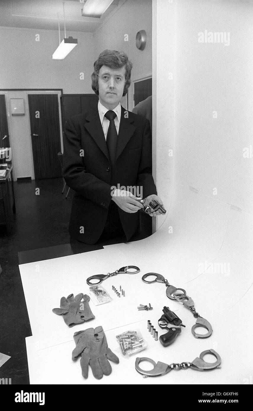 Exhibits officer David Bowen of 'A' Division crime squad, Metropolitan Police, with articles found in the possession of Ian Ball, 26, who pleaded guilty at the Old Bailey to attempting to kidnap Princess Anne, attempted murder of two police officers and wounding two civilians. Det Con David Bowen holds a .22 Astra gun of Spanish make. On the table are handcuffs, two pairs of which are locked together to provide leg shackles, keys for the handcuffs, gloves worn by Ball during the incident, six spent rounds, three live rounds and 39 spares for the .22 gun and a .38 Astra with five spent rounds Stock Photo