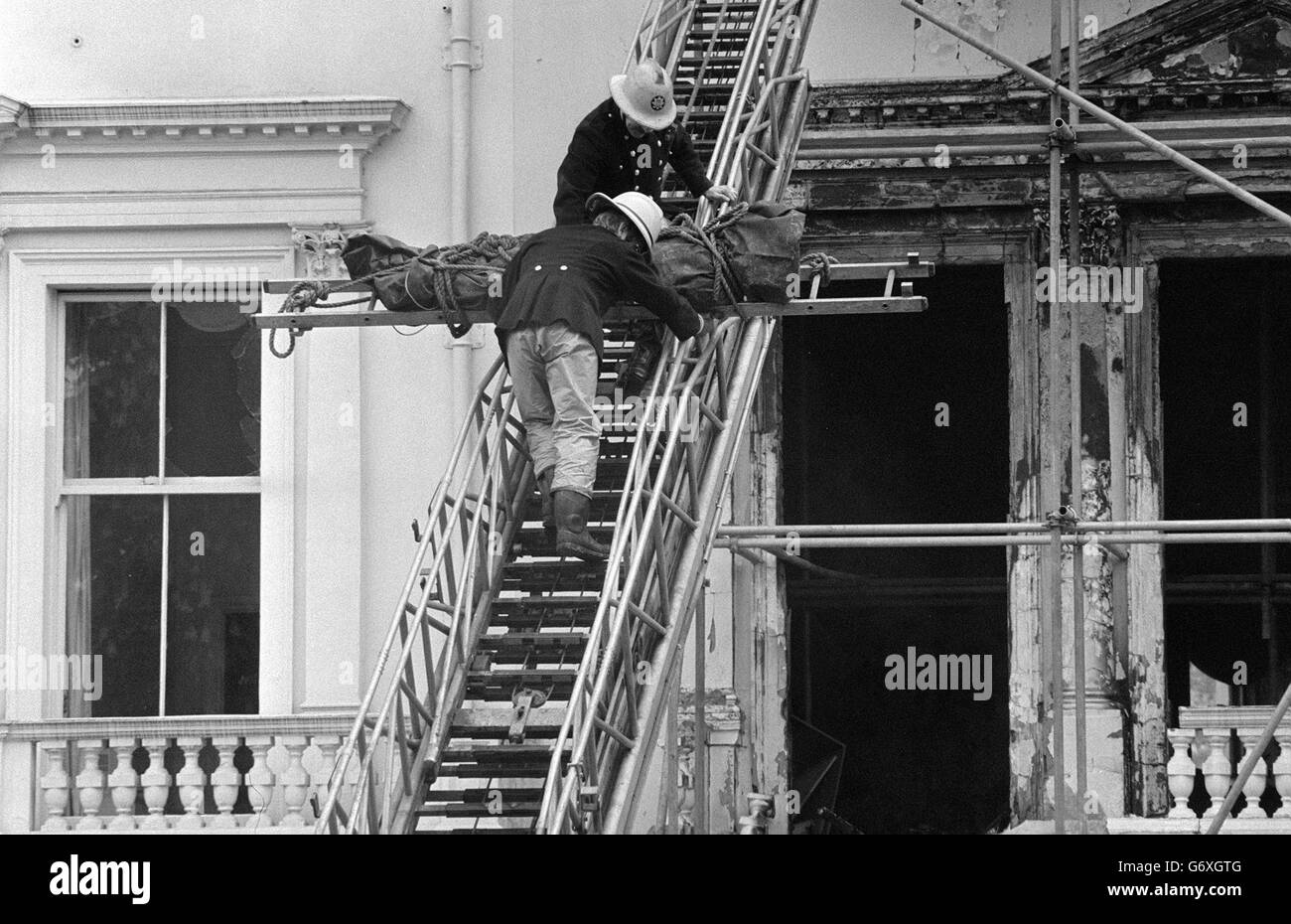 Firemen removing one of two bodies so far found in the burnt-out remains of the Iranian Embassy in London. The corpse, wrapped in a dark green body bag, was lowered from a second floor front window of the building in Princes gate, Kensington, and taken away by a hearse. Stock Photo