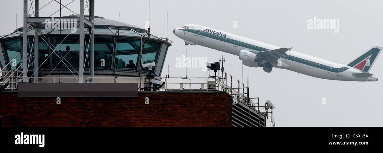 An Alitalia aircraft taking-off from London's Heathrow airport passes the control tower which is to be decommissioned in 2006, by which time it will have been in use for more than 50 years. The building is 38.5m (127 feet 6 inches) tall and was required to give a good view of the airfield. Last year it handled 463,605 movements involving 64.3 million passengers. Its record day was on June 28, 2002, with 1,365 movements. The Visual Control Room (VCR) at the top holds five controllers, their supervisor and four support staff. The new 87 metre tall Control Tower - effectively a five storey Stock Photo