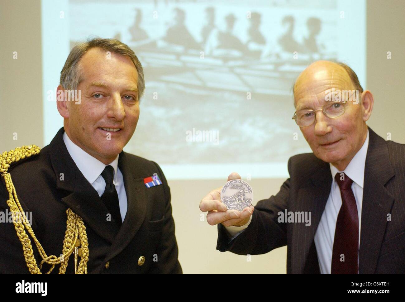Brian Mills (right) brother of late 'Cockleshell hero' Bill Mills, receives a medallion on his brother's behalf from Admiral Sir Jonathan Band, Commander in Chief, Fleet, commemorating the daring raid he took part in, in 1942. Marine Mills was one of 10 Royal Marine commandos assigned to attack enemy German ships moored at the port of Bordeaux, using five two-man cockleshell canoes launched from the Royal Navy submarine HMS Tuna. Marine Mills and his partner were caught by the French police, handed over to the Germans and executed three months later. Stock Photo