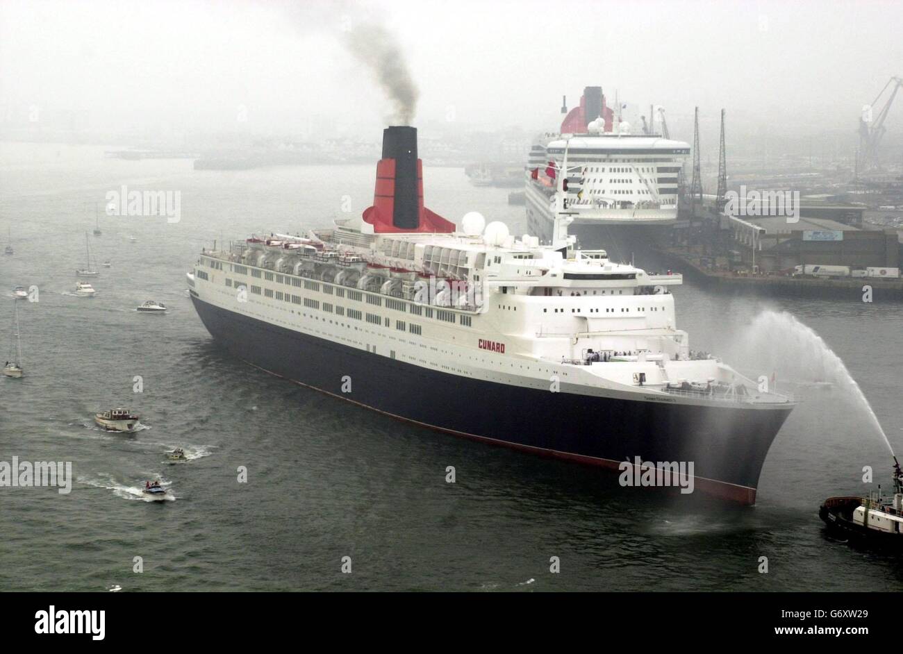 The QE2 passing the QM2 at Southampton. The end of an era in cruising was being marked today in a ceremony involving the QE2 and Cunard's new superliner the 150,000-tonne Queen Mary 2 (QM2). At the ceremony, attended by Deputy Prime Minister John Prescott, Cunard's flagship status was being passed from the 35-year-old QE2 to the 540 million QM2 which was officially named by the Queen in January this year. Stock Photo