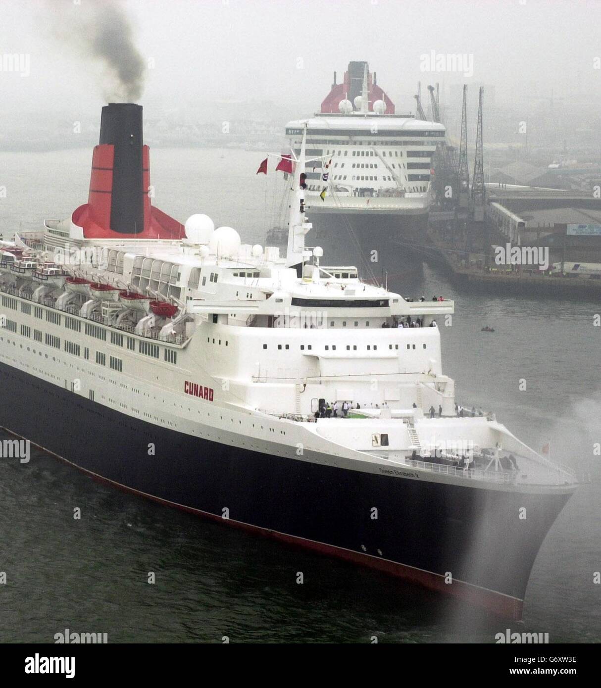The QE2 passing the QM2 at Southampton. The end of an era in cruising was being marked today in a ceremony involving the QE2 and Cunard's new superliner the 150,000-tonne Queen Mary 2 (QM2). At the ceremony, attended by Deputy Prime Minister John Prescott, Cunard's flagship status was being passed from the 35-year-old QE2 to the 540 million QM2 which was officially named by the Queen in January this year. Stock Photo