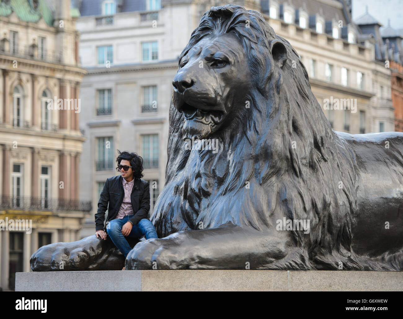 A man sits on one of the lion statues in Trafalgar Square, in central London. PRESS ASSOCIATION Photo. Picture date: Saturday March 22, 2014. Photo credit should read: Dominic Lipinski/PA Wire Stock Photo