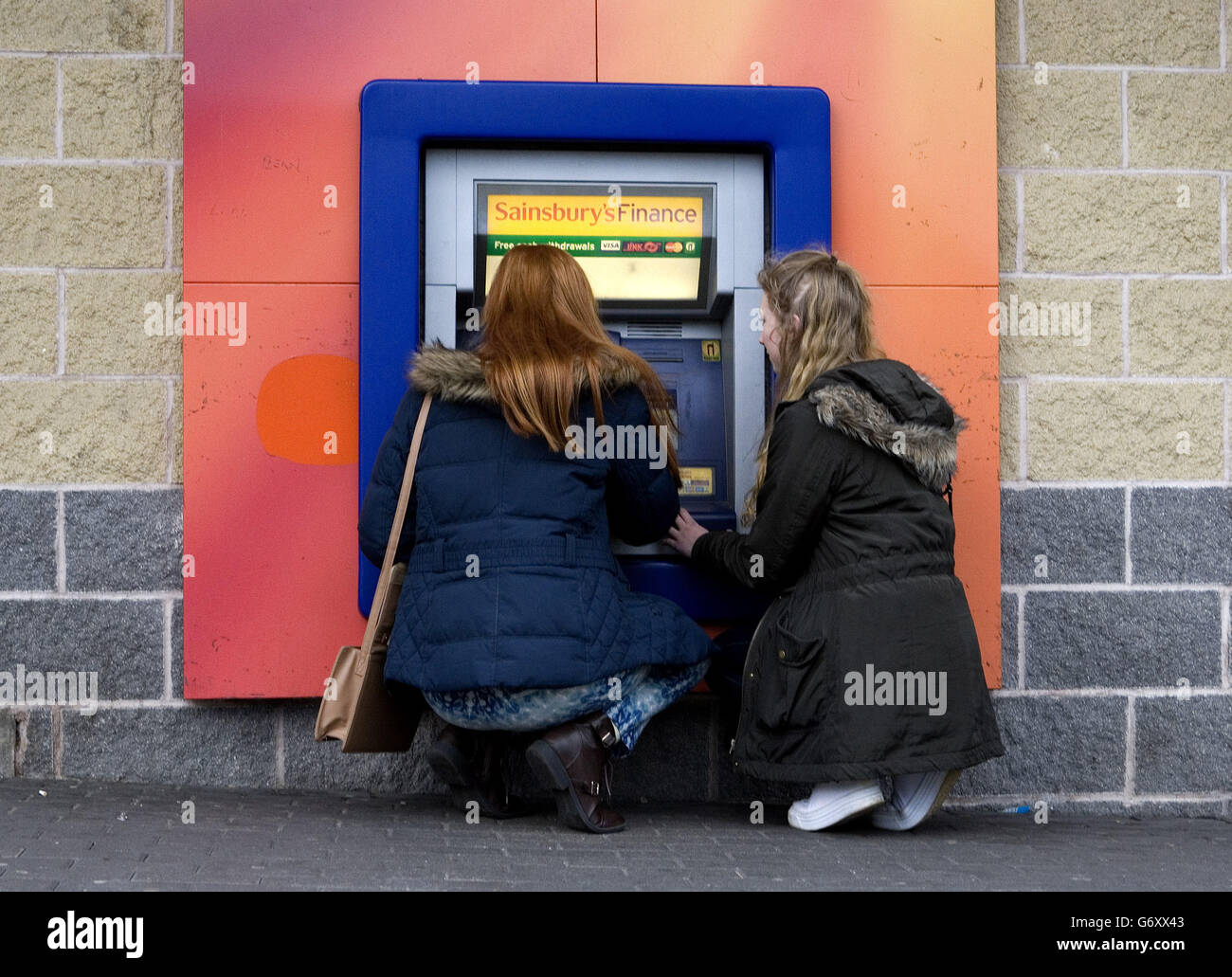 Katie Eames, 17, (left) and Laura Clark, 17, use the Sainsburys bank cash machine on Nuthall Road, Nottingham. Stock Photo