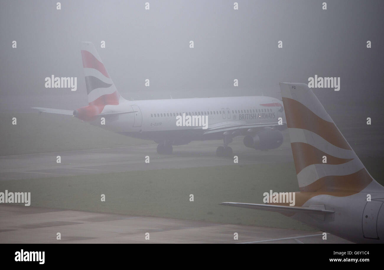 Planes taxi in fog at Terminal 5 after the weather has led to delays and cancellations at Heathrow Airport, west London. Stock Photo