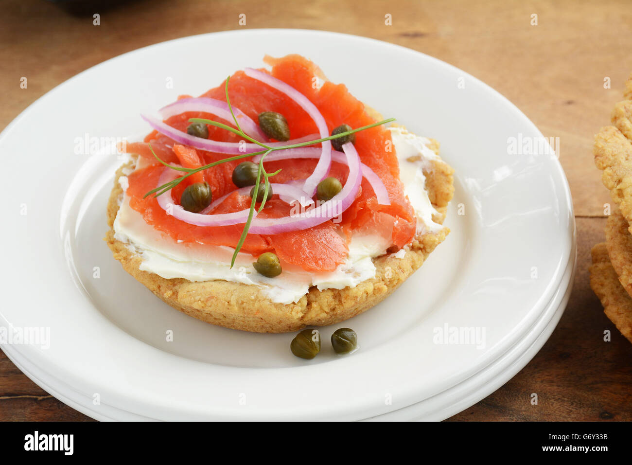 Healthy home made gluten free biscuit with smoked salmon lox, cream cheese, capers and red onion slices on white plate in horizo Stock Photo