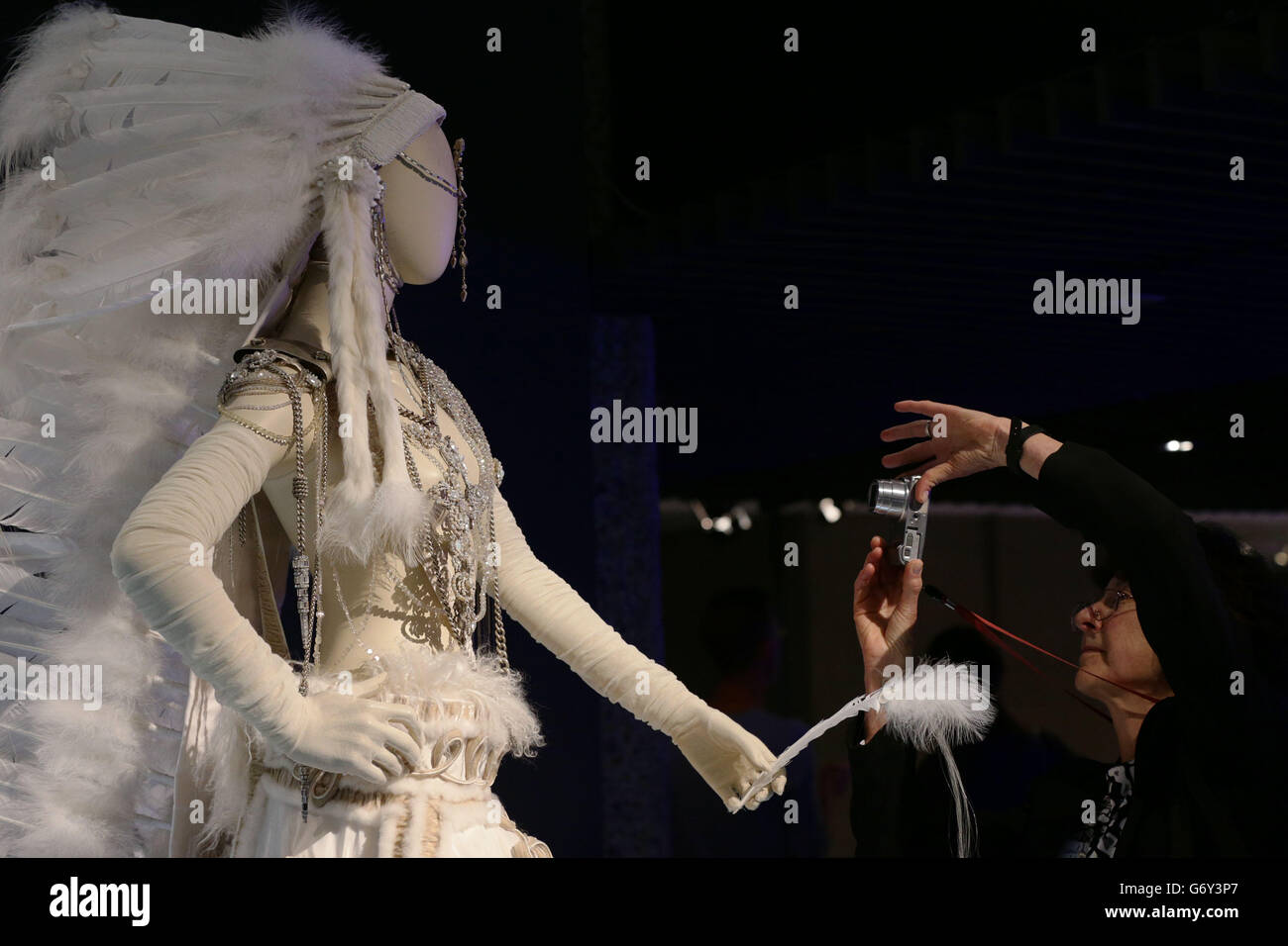 A visitor takes a photograph of clothes on display, during a media view of 'The Fashion World of Jean Paul Gaultier: From the Sidewalk to the Catwalk' - the first major exhibition devoted to the celebrated French couturier, including costumes for film and performance including the conical bra and corsets Madonna wore during her 1990 Blond Ambition World Tour, stage costumes designed for Kylie Minogue as well as pieces created for the films of Pedro Almodovar among others - at Barbican Art Gallery in London. Stock Photo