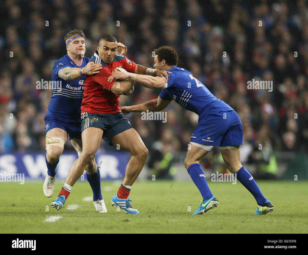 Munster's Simon Zebo, is tackled by Leinster's Jamie Heaslip (left) and Zane Kirchner (right) during the RaboDirect PRO12 match at the Aviva Stadium, Dublin, Ireland. Stock Photo