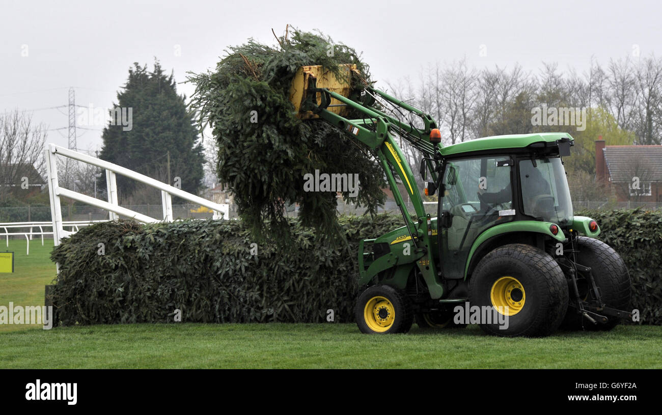 A tractor carries a load of spruce used to construct the Aintree Grand National fences, across the course during a preparation day ahead of the 2014 Crabbie's Grand National Festival at Aintree Racecourse, Liverpool. Stock Photo