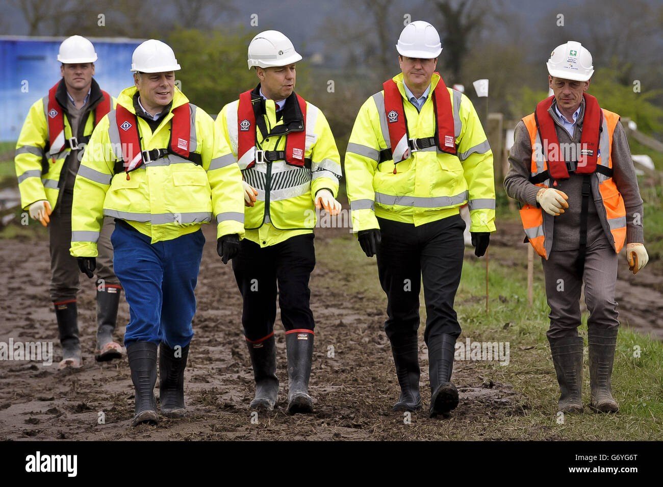 Prime Minister David Cameron (second right) wears full PPE including steel toe-capped boots, high-viz vest, life-jacket, gloves and hard-hat as he arrives on site at the dredging works on the River Parrett, near Burrowbridge, Somerset, where repair and recovery from the floods earlier in 2014 are taking place. Stock Photo