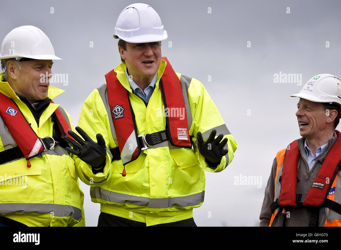 Prime Minister David Cameron (centre) wears full PPE including steel toe-capped boots, high-viz vest, life-jacket, gloves and hard-hat as he arrives on site at the dredging works on the River Parrett, near Burrowbridge, Somerset, where repair and recovery from the floods earlier in 2014 are taking place. Stock Photo