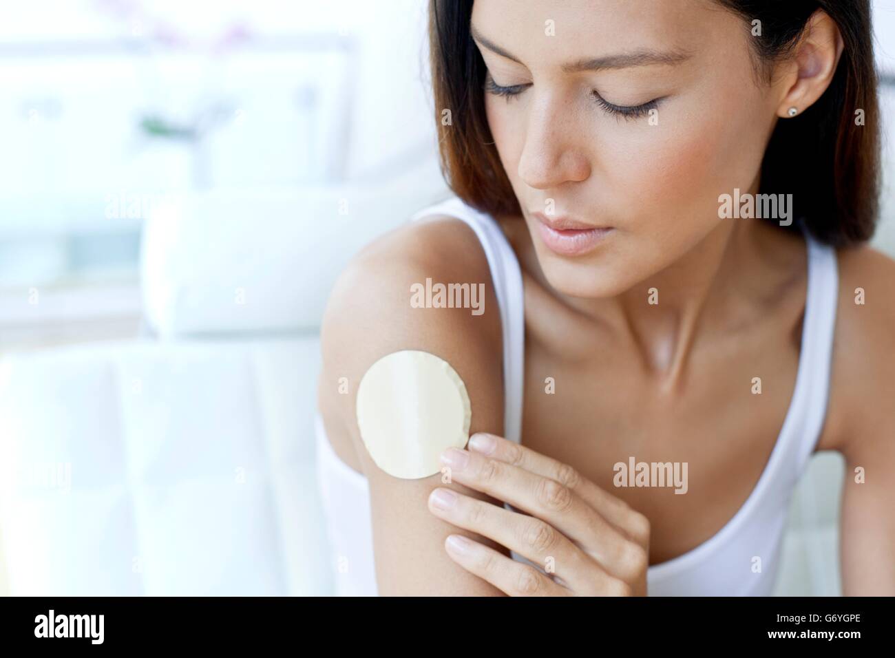MODEL RELEASED. Young woman wearing a nicotine patch on her arm. Stock Photo