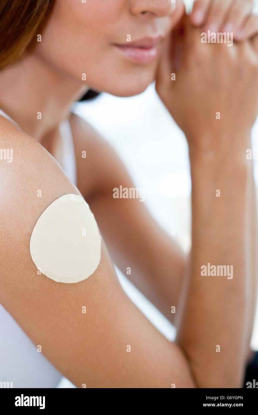 MODEL RELEASED. Young woman wearing a nicotine patch on her arm. Stock Photo
