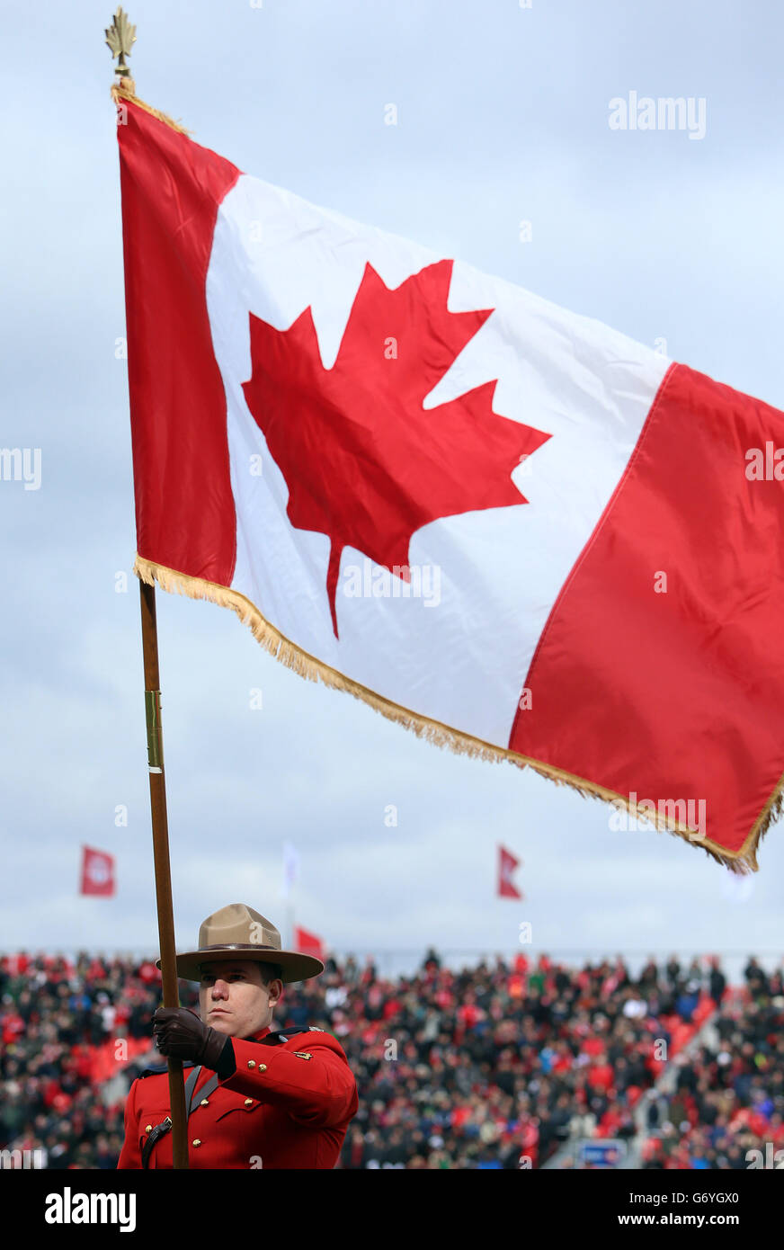 A mountie and the canada flag during the national anthems hires stock