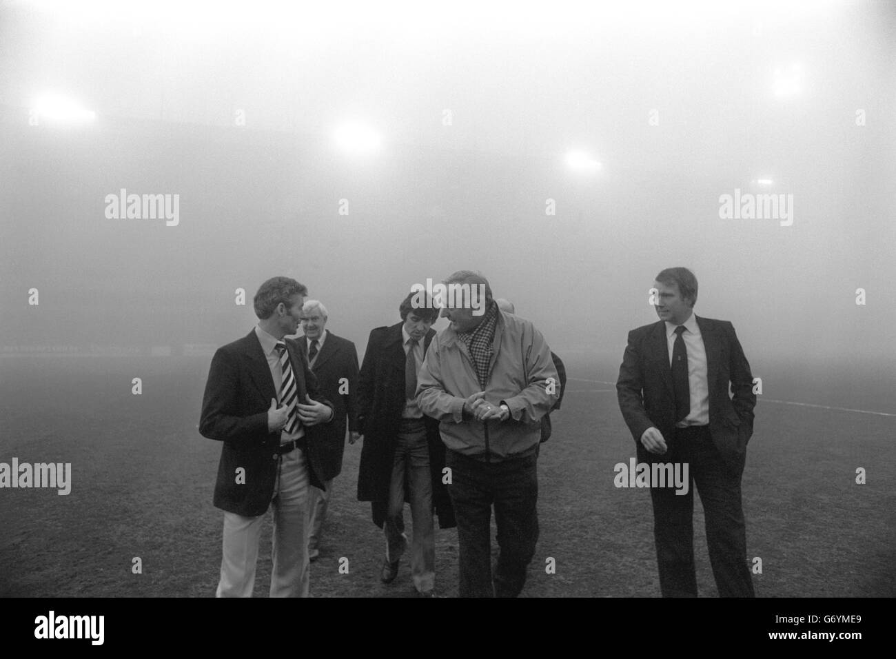 In the background the fog obscures the floodlights at City Ground in Nottingham, when Nottingham Forest assistant manager Peter Taylor (centre) leads the inspection party with D. Richardson (l), the referee for the FA Cup third round match, and Wrexham manager Mel Sutton (3rd left) closely following him. The FA Cup third round game is to be postponed until tomorrow. Stock Photo