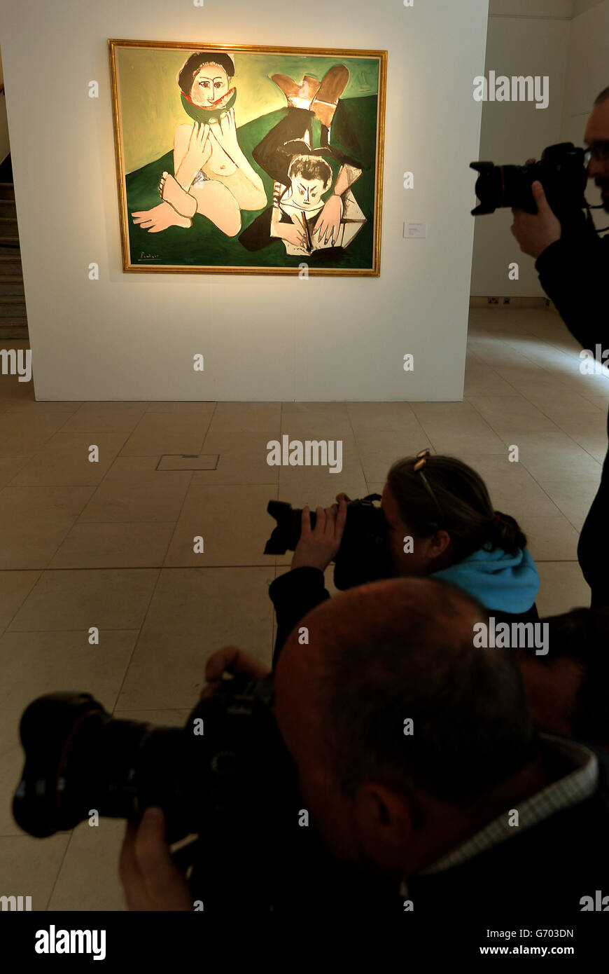 A group of press photographers work close to a Picasso painting, titled 'Mangeuse de pasteque et homme ecrivant' that will be auctioned in New York on 6th May, and has an estimated sale value of between $7-10million, at the Christie's showroom in central London. Stock Photo