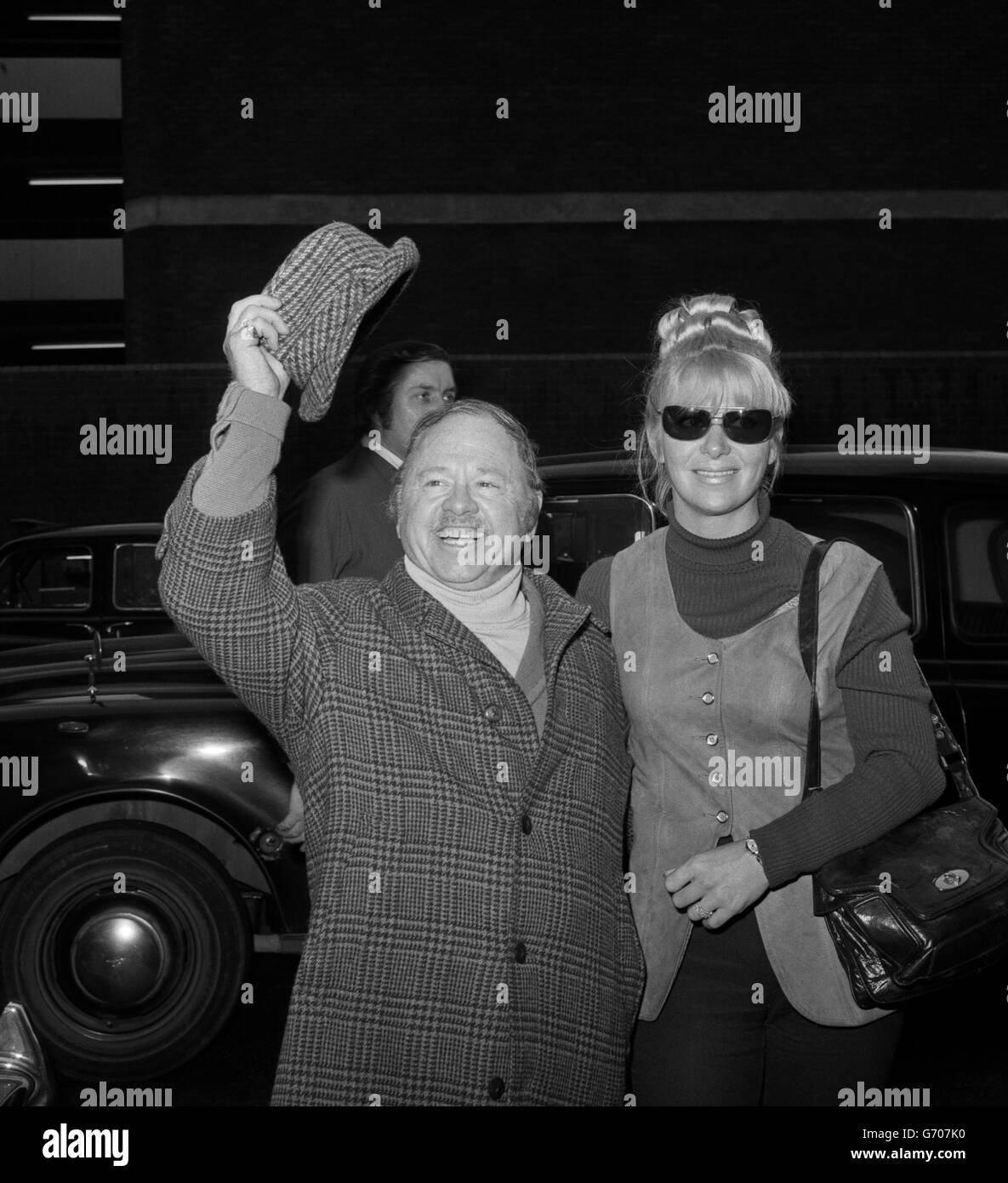 Andy Hardy, alias the now-50-year-old Hollywood actor, Mickey Rooney, gives a glad-to-be-here wave on arrival at Heathrow Airport, alongside his wife Caroline. Rooney, who has been married seven times, is in London for a one-day visit before flying to Malta to make a film, called 'Scandal', in which he will portray a retired gangster. Stock Photo