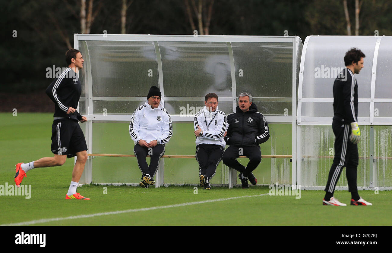 Chelsea manager Jose Mourinho (centre right) sits on the bench with coaches Steve Holland (centre) and Sivino Louro (left) as players warm up during a training session at Cobham Training Ground, Surrey. Stock Photo