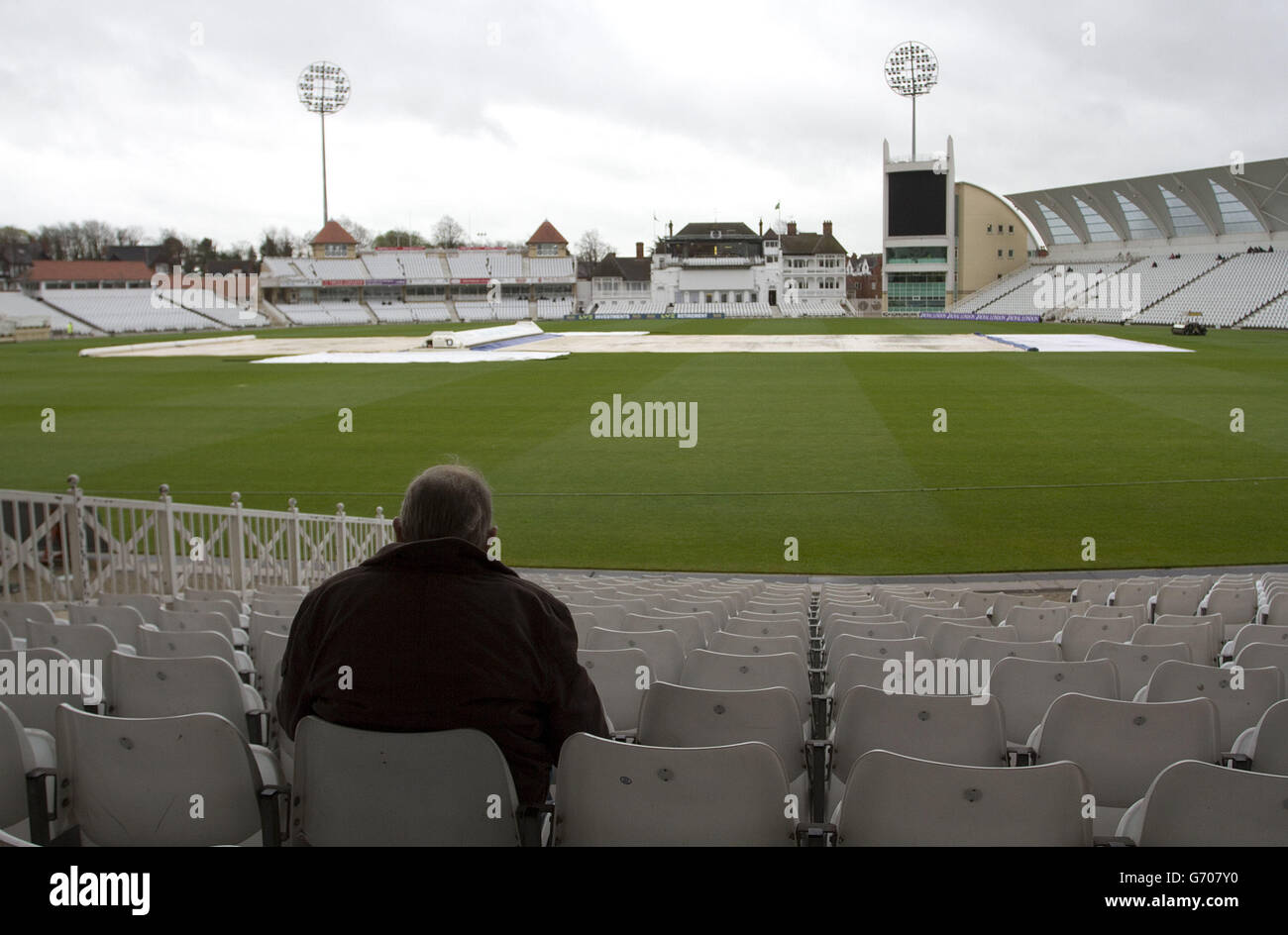 A fan shelters at the back of the stands as rain delays the start of play during the LV=County Championship, Division One match at Trent Bridge, Nottingham. Stock Photo