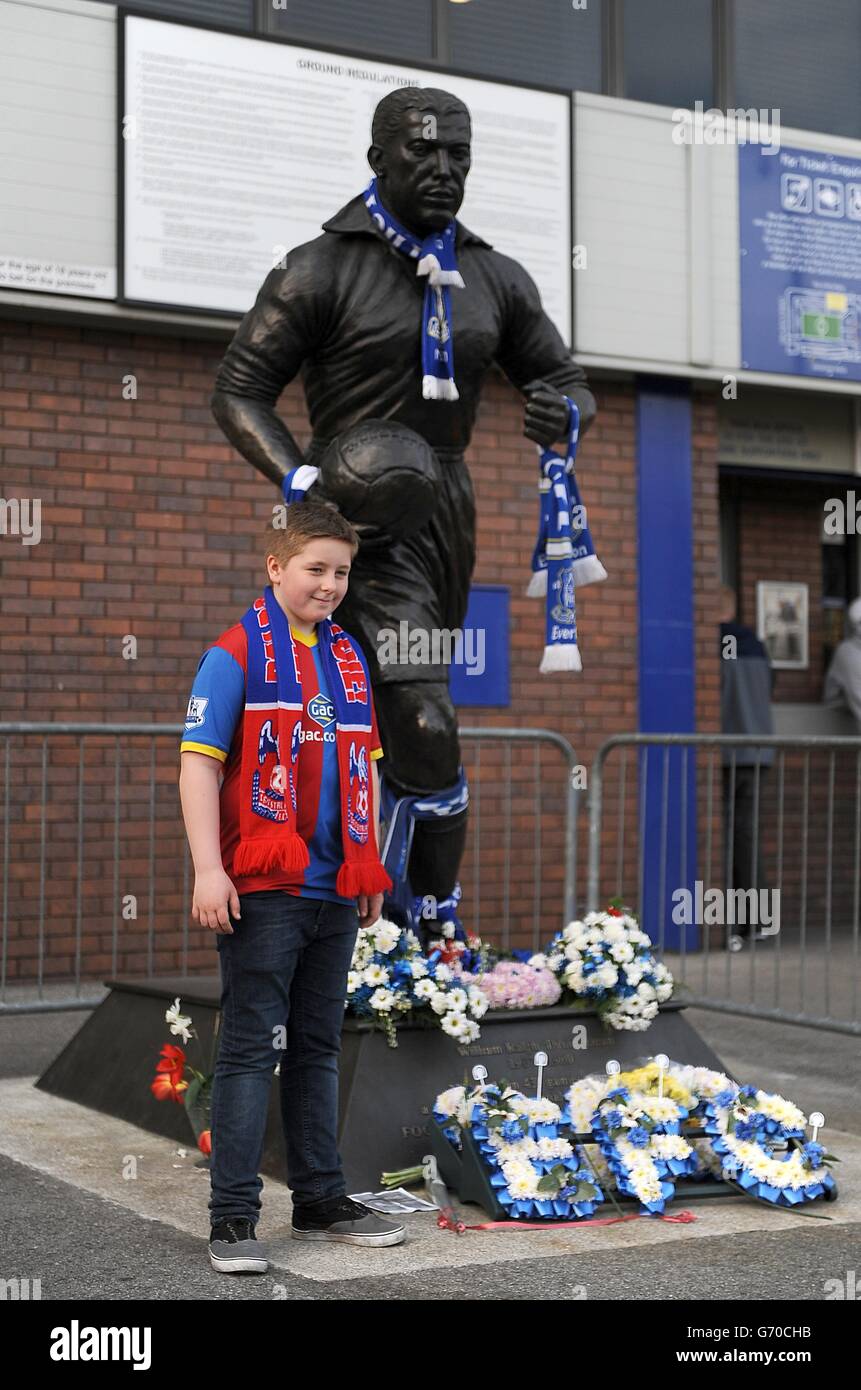 Soccer - Barclays Premier League - Everton v Crystal Palace - Goodison Park. A young Crystal Palace fan poses next to the Dixie Dean statue covered in tributes, before the game Stock Photo