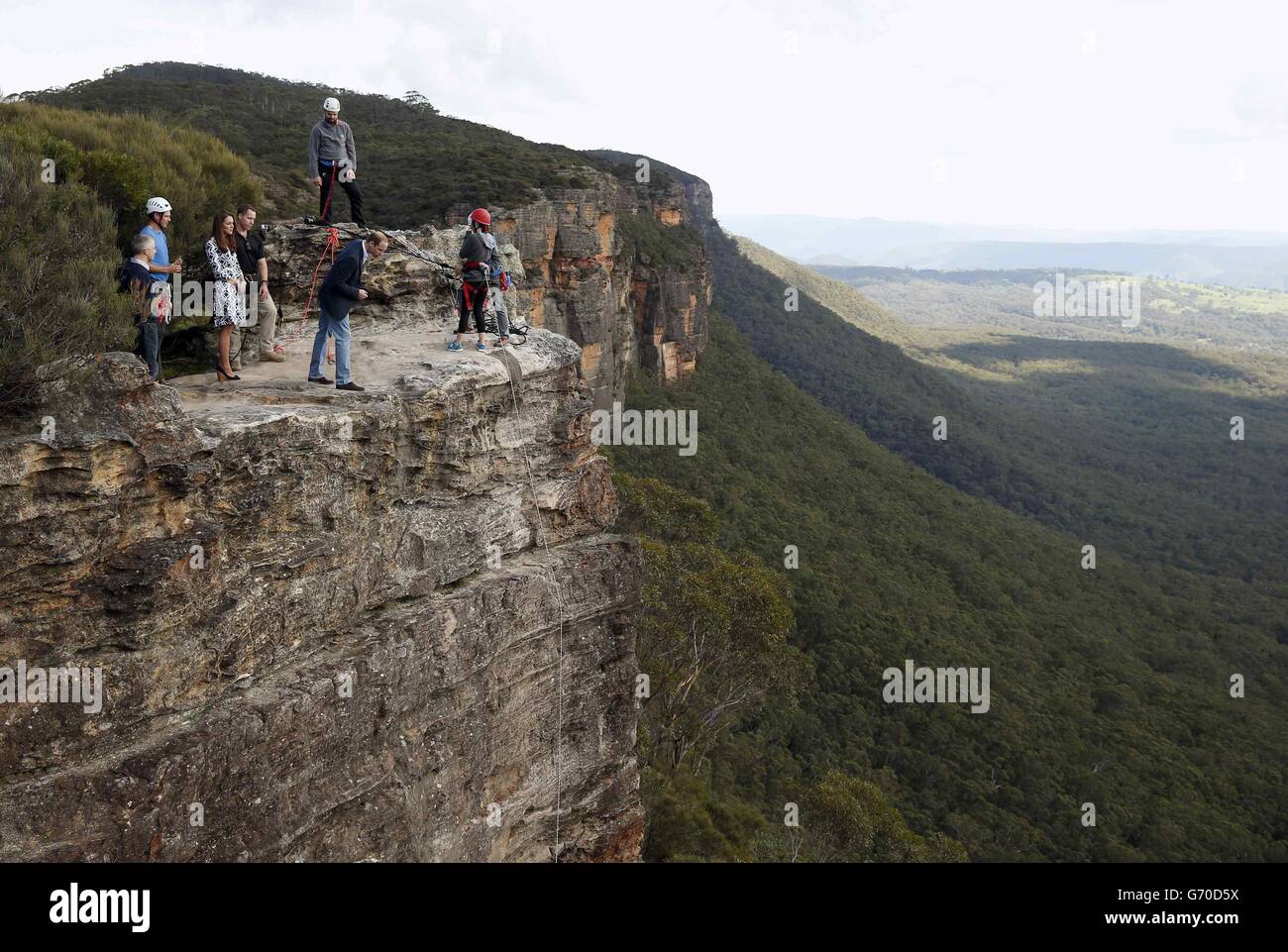 The Duke of Cambridge (centre) looks over the edge of a cliff as he and the Duchess of Cambridge visit the Narrow Neck Lookout and observes abseiling by the Mountain Youth Services group in the Blue Mountains town of Katoomba, west of Sydney. Stock Photo