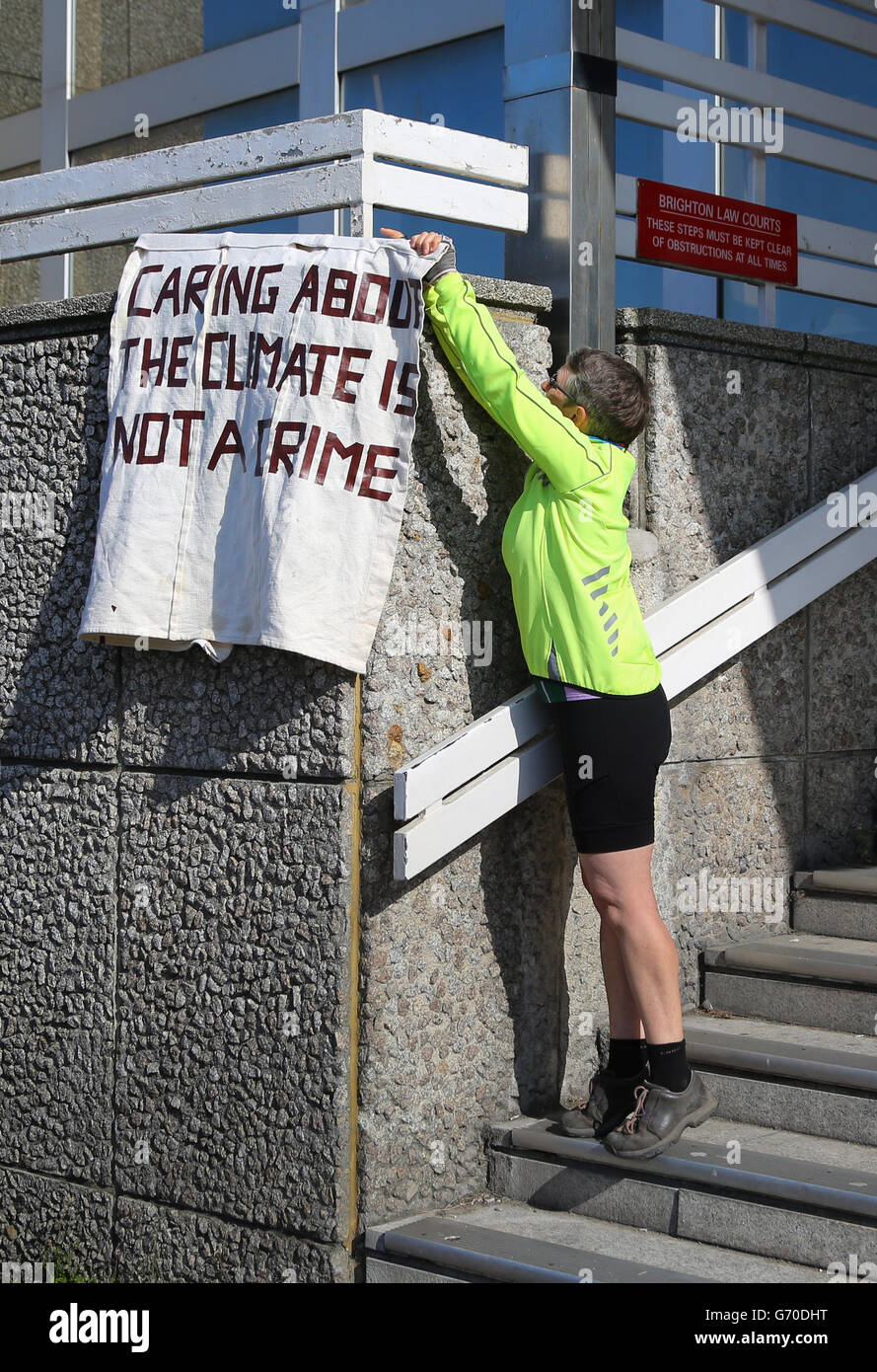 An environmental campaigner ties a banner to Brighton Magistrates Court in East Sussex, as the verdict in the trial of Green MP Caroline Lucas over public order offences allegedly committed during anti-fracking protests in Balcombe last year is heard later today. Stock Photo