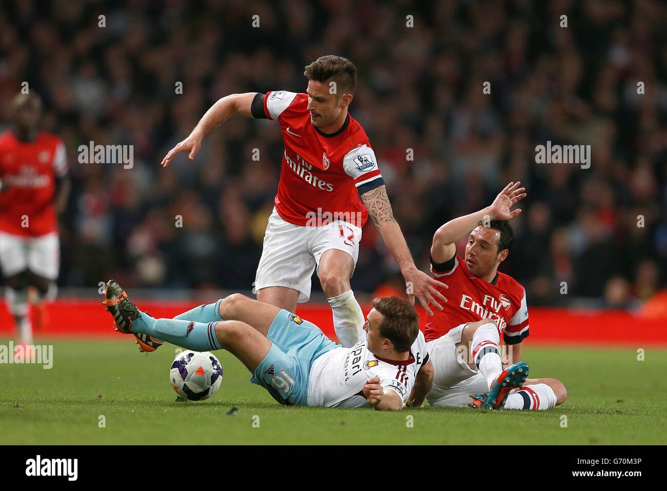 West Ham United's Mark Noble (centre) slides in to challenge Arsenal's Santi Cazorla (right) and Olivier Giroud Stock Photo