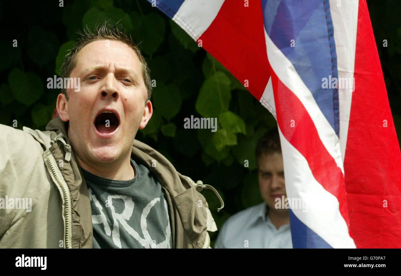 Right wing protesters waving Union Jack flags shout at Muslims during Friday prayers outside a London mosque. Around 20 men, claiming to be from a group called the United British Alliance jeered and shouted anti-Muslim slogans from behind fences set up by police outside the Finsbury Park mosque. There were scuffles after a few protesters seemed to infiltrate the street in which prayers were being held, outside the north London mosque where radical cleric Abu Hamza was based before his arrest. Stock Photo