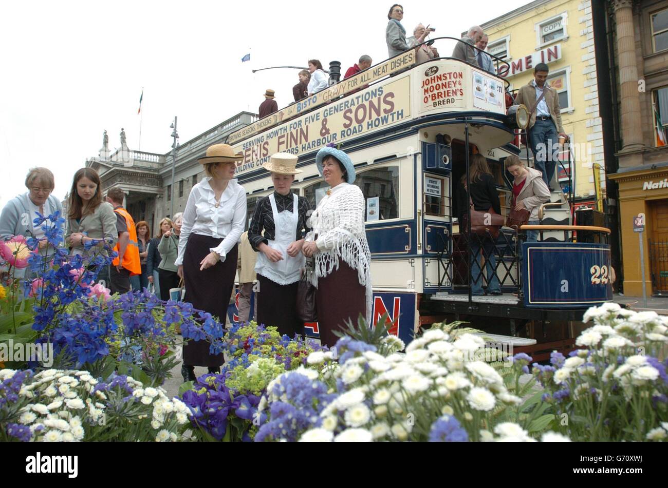 Members of the public and actors dressed in Edwardian costume browse a flower stall beside a parked tram, to celebrate the centenary of Bloomsday - the key event in the author's definitive novel, Ulysses. On June 16, 1904, Leopold Bloom, the book's pivotal figure, embarked on a walk around Dublin, describing almost every step of the way and in recent years, celebrating that stroll has been turned into a Dublin industry. Stock Photo